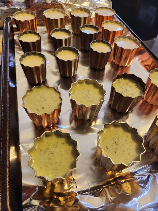 Canelé molds filled with the batter for canelés ready to be put into the oven.